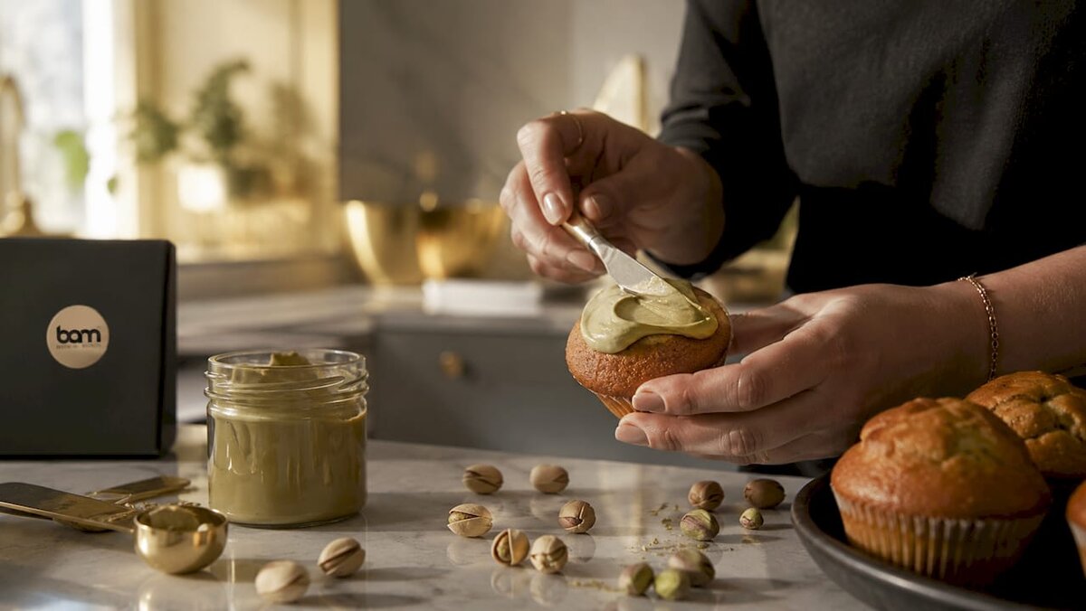 Mani che spalmano la crema al pistacchio su un muffin